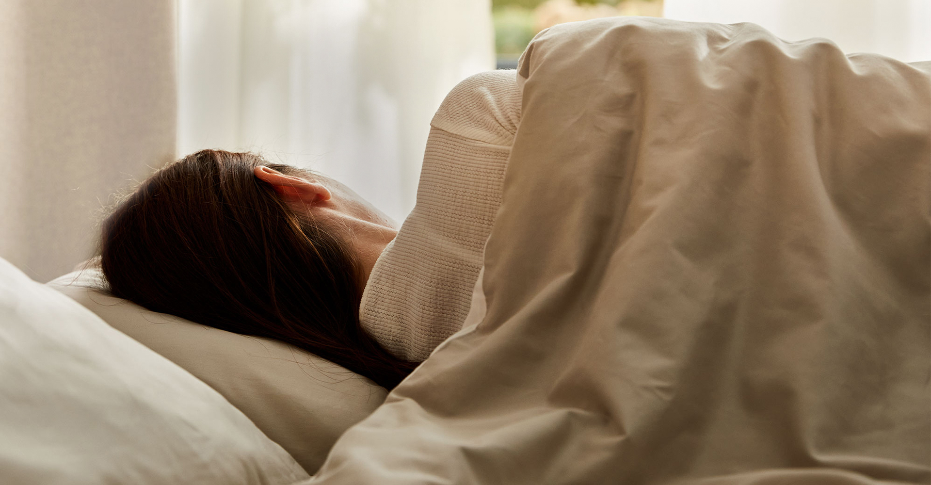 Frau liegt zugedeckt im Bett