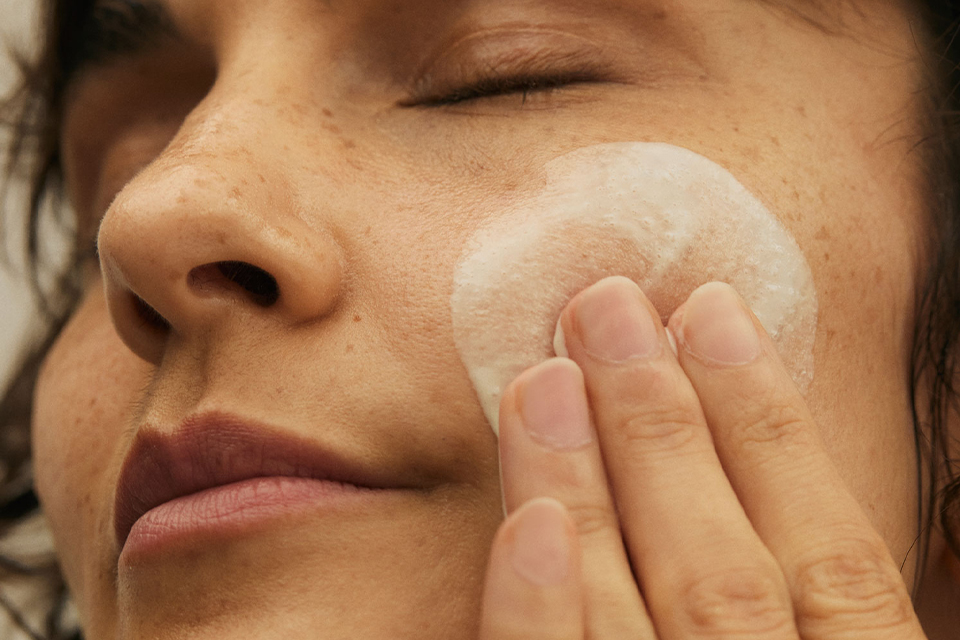 Nahaufnahme eines Frauengesichts mit Creme auf der Wange