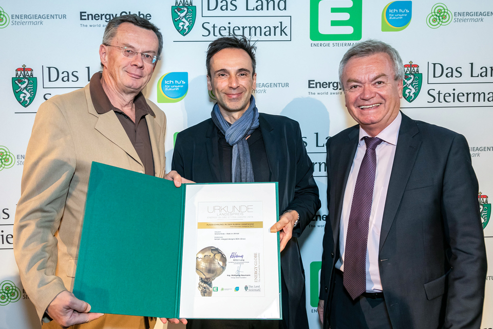 Drei Männer präsentieren Urkunde bei Preisverleihung