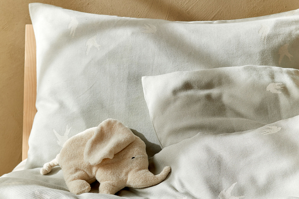 Weiße Bettwäsche mit einem kleinen Kuscheltierelefanten auf einem Bett