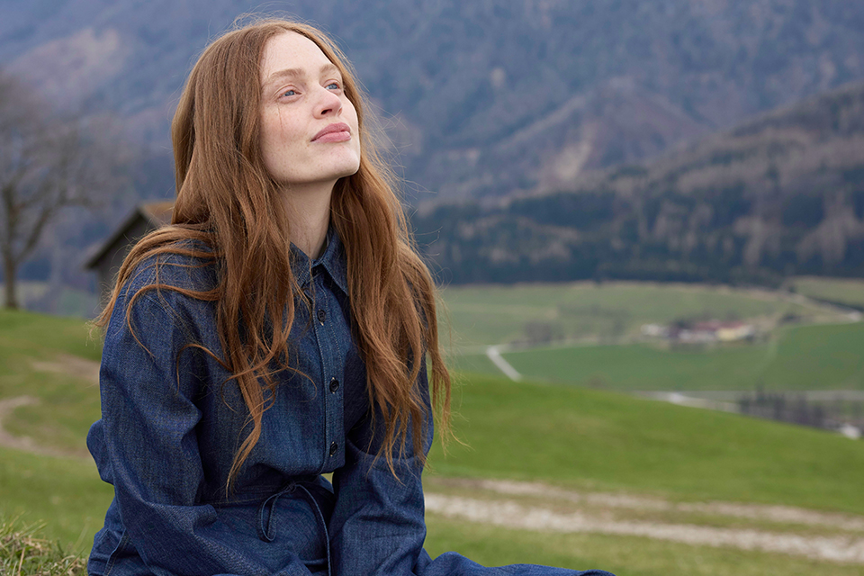 Frau genießt frische Bergluft mit geschlossenen Augen in Natur