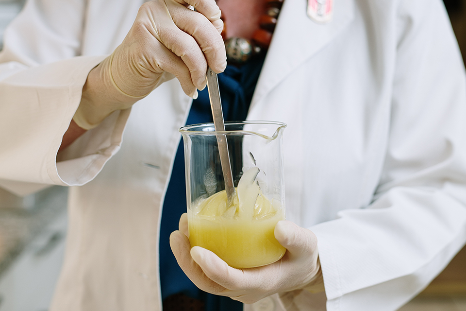 Hände halten ein Gefäß mit gelartiger Textur