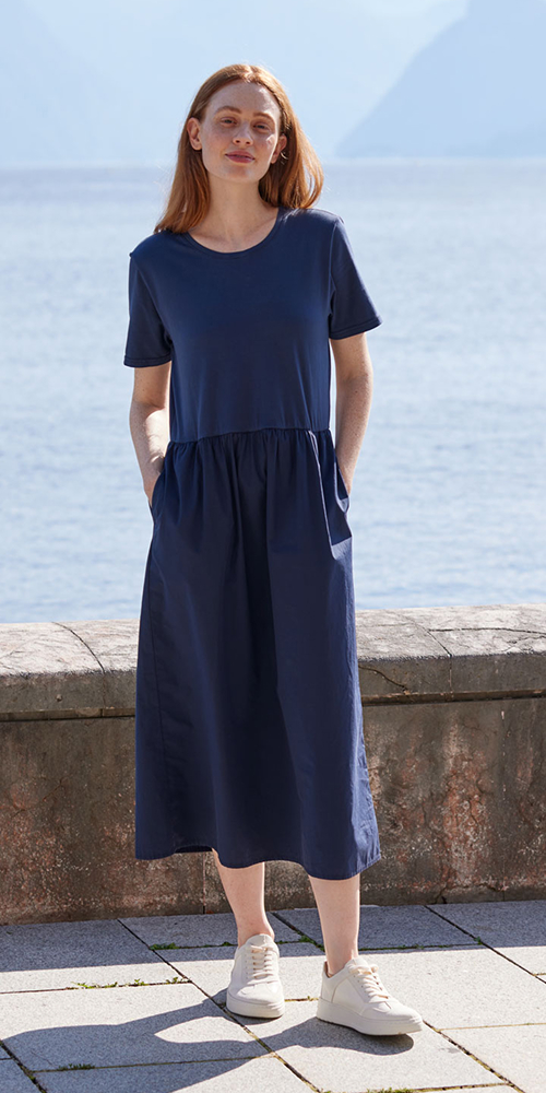 Frau trägt dunkelblaues Kleid und steht vor einem See