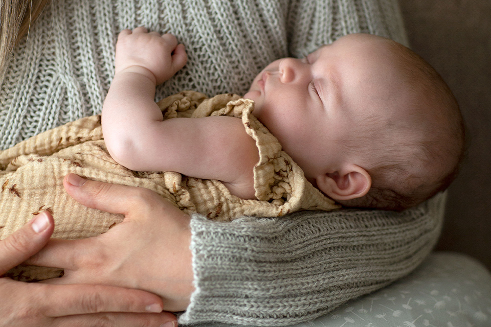 Baby schläft in den Armen seiner Mutter