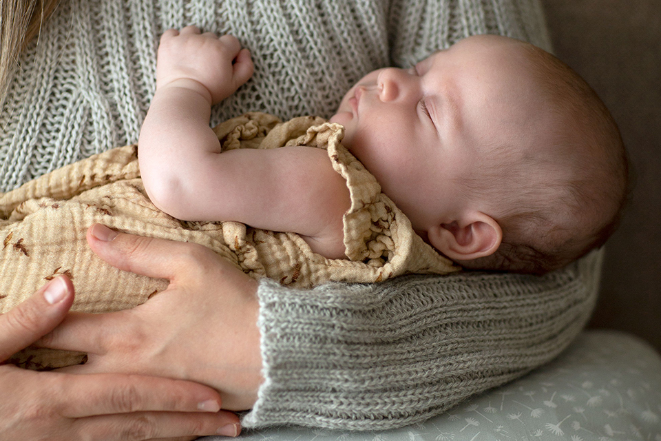 Baby schläft in den Armen seiner Mutter