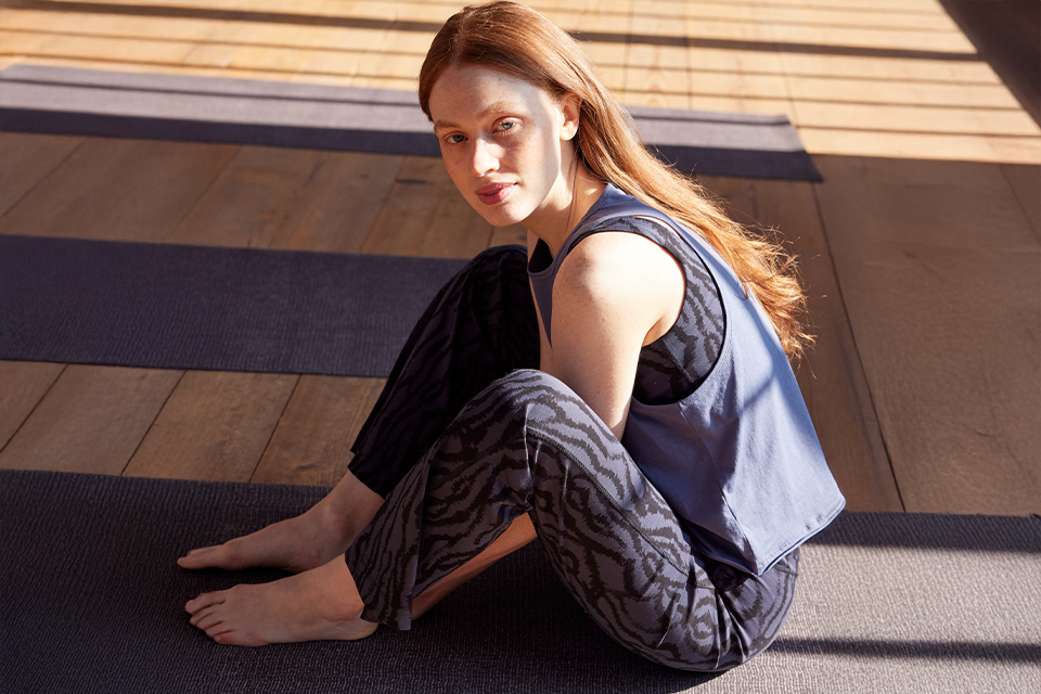 Frau sitzt auf Matte und blickt ruhig zur Seite
