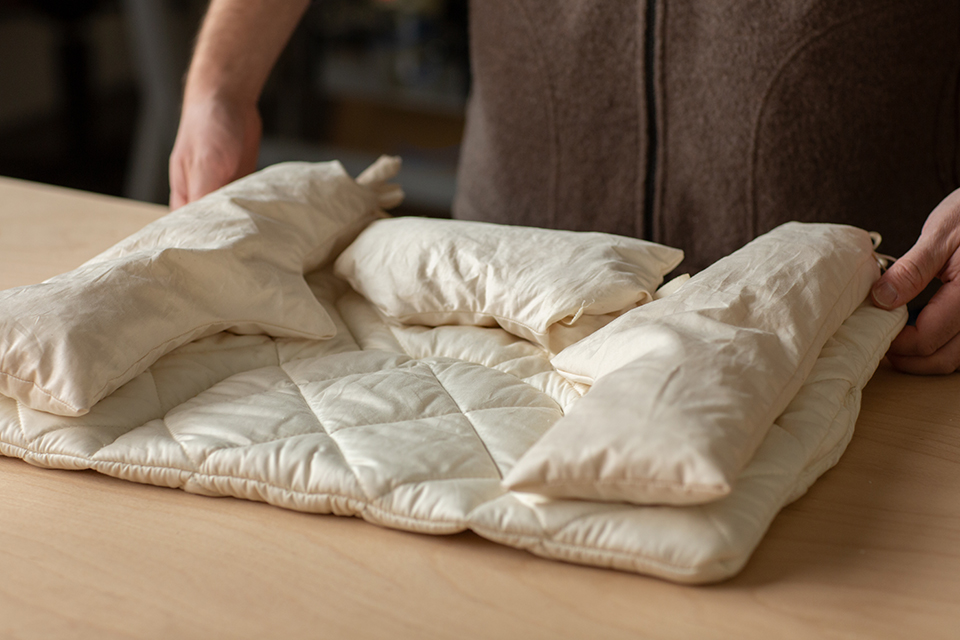 Komfortkissen Ergo liegt auf einem Tisch und wird von 2 Händen gehalten