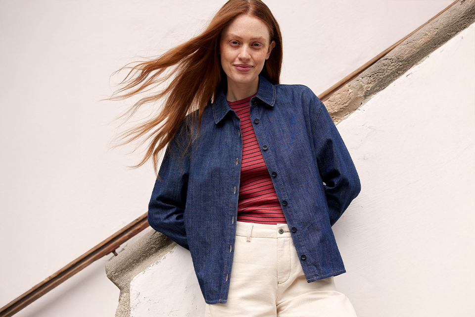 Frau in dunkler Jeansjacke lehnt an einer Treppe