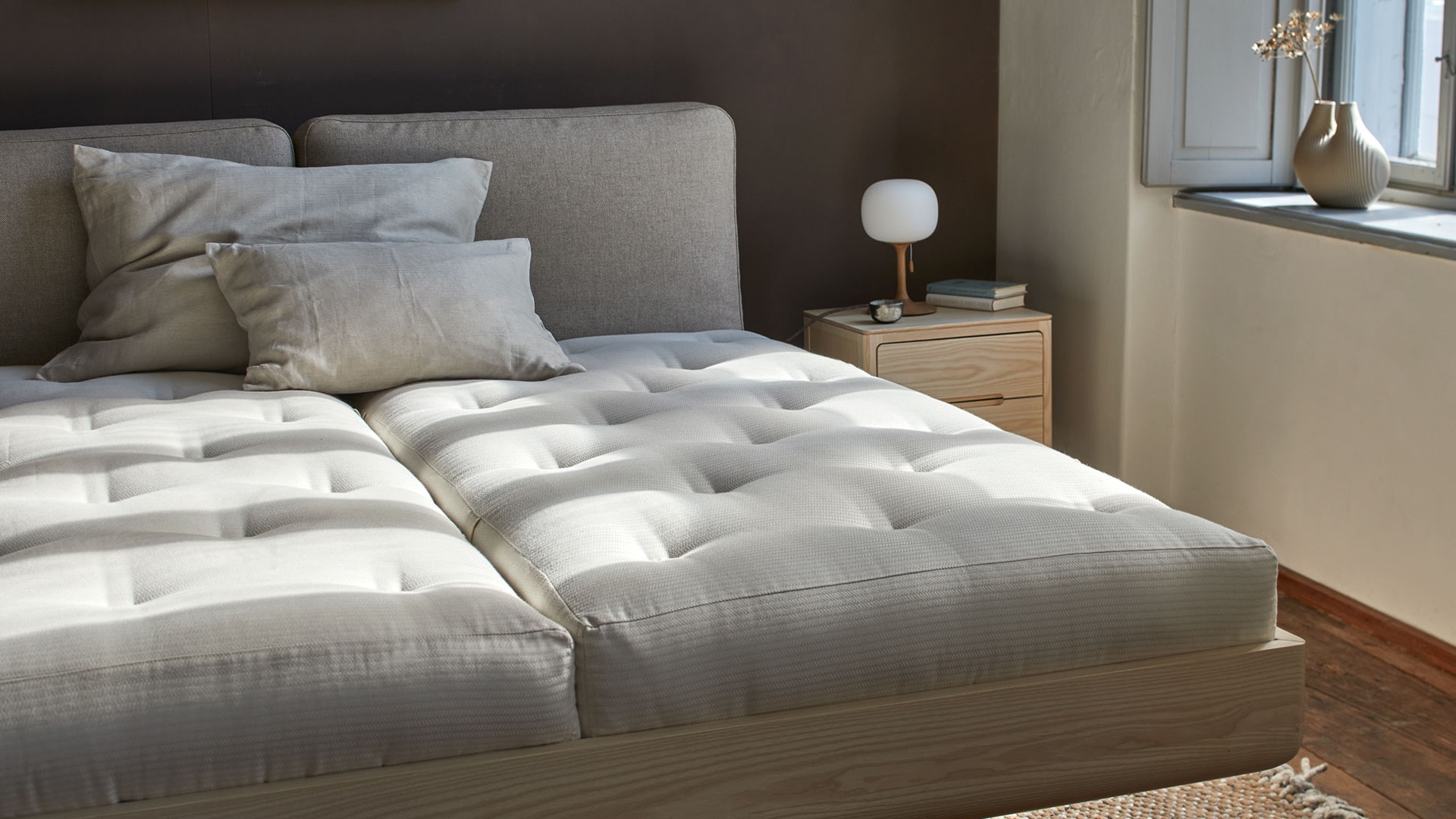 Hochwertiges Bett Almara mit zwei ökologischen Naturmatratzen vor einem Fenster