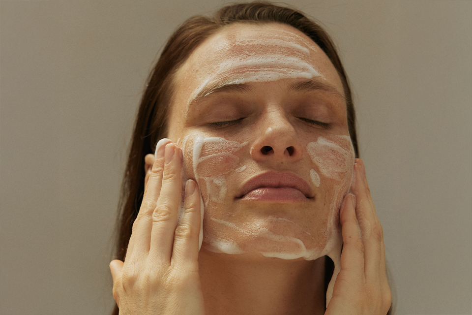 Frau reinigt ihr Gesicht mit einem Reinigungsschaum