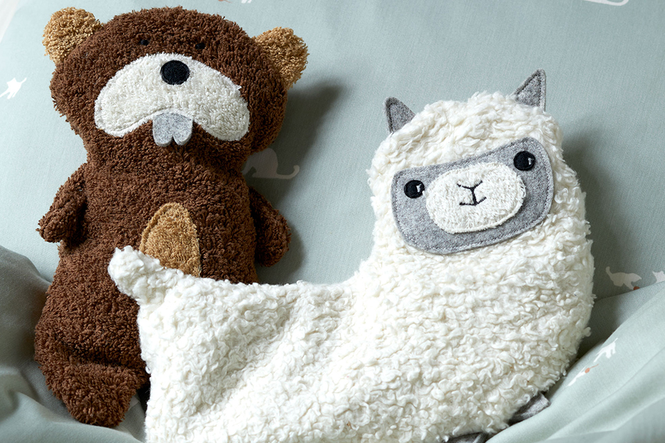 Kuscheltiere in Biber und Lama Form Form auf einer decke sitzend