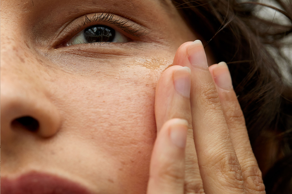 Linke Hälfte eines Frauengesichtes mit einer Hand an der Wange