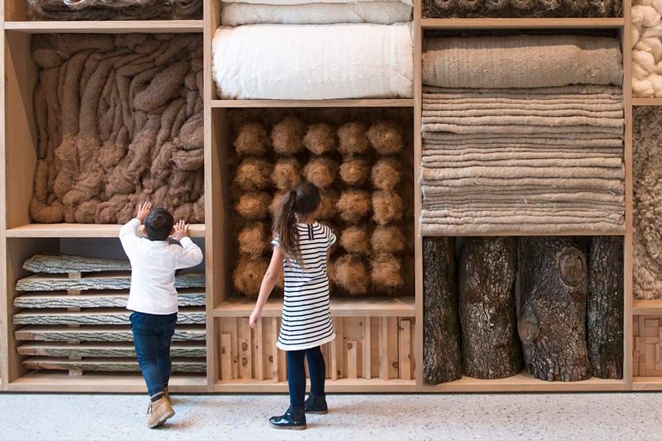 Zwei Kinder vor einer Wand aus verschiedenen Naturmaterialien