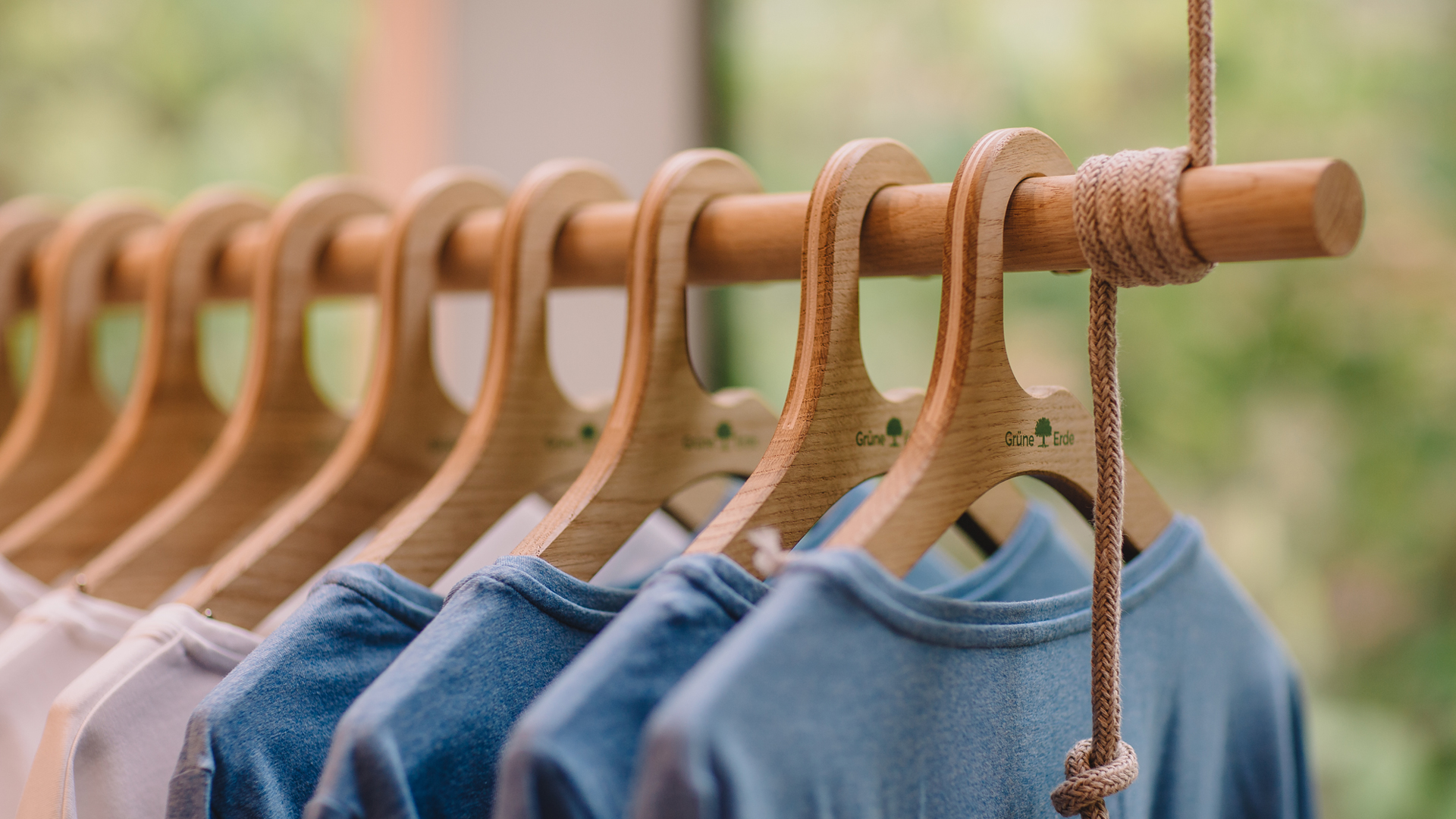 Kleidung auf Holzbügeln an Kleiderstange im Geschäft