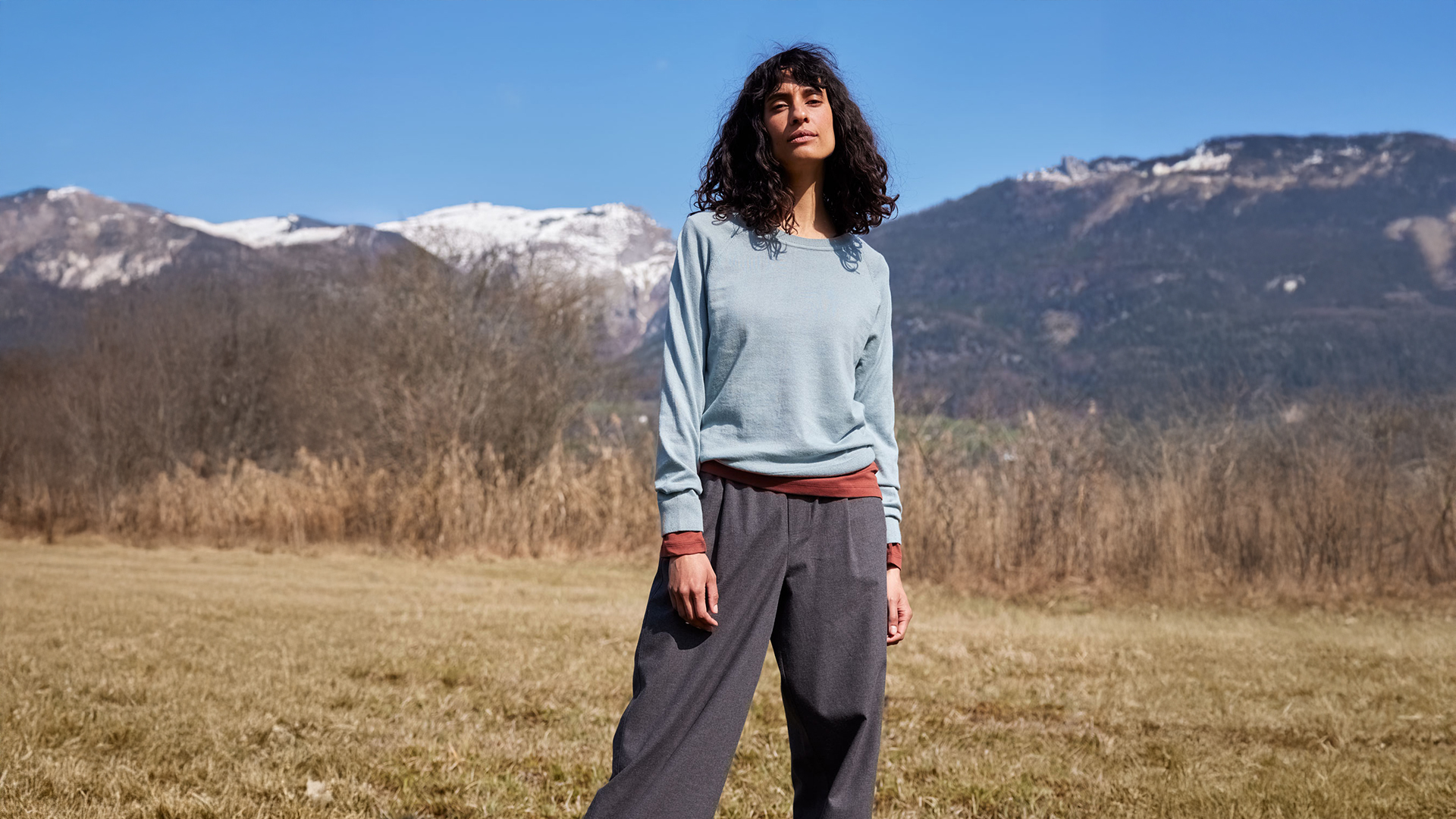 Frau in bequemer Kleidung steht vor Berglandschaft