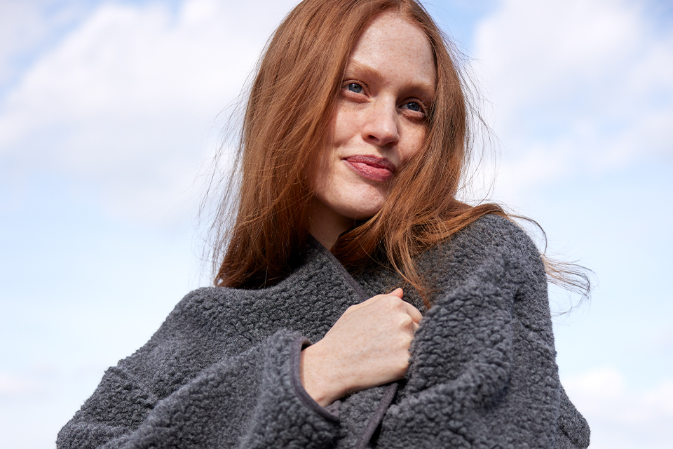 Frau mit grauem Pullover berührt weich wirkenden Stoff