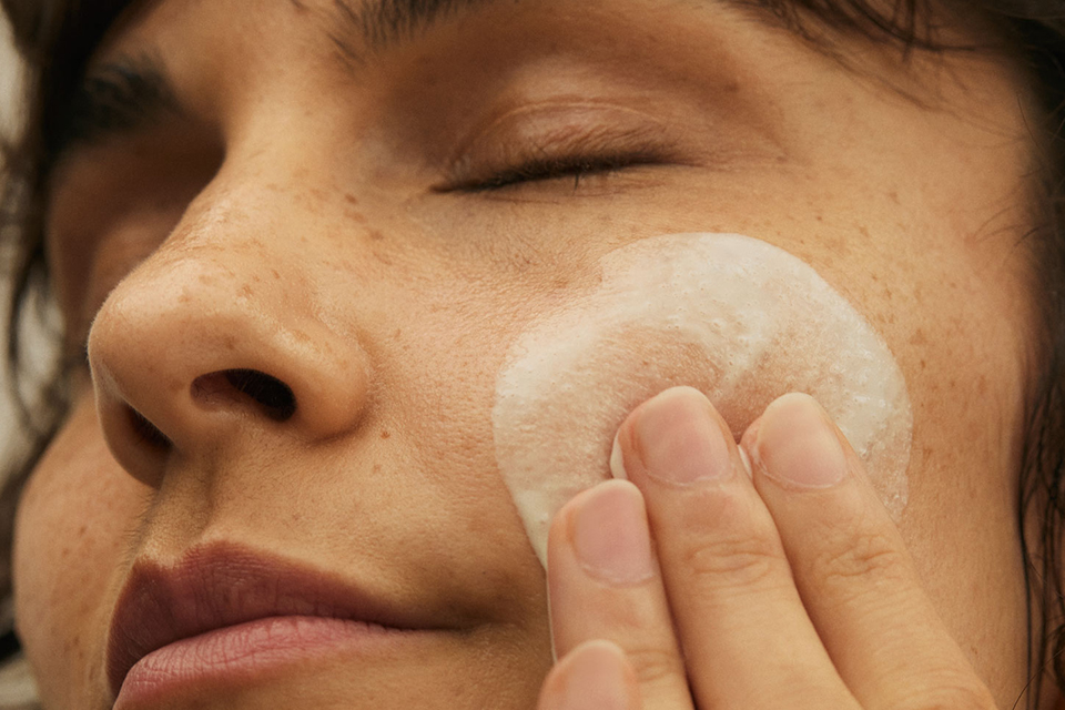 Nahaufnahme eines Frauengesichts mit Creme auf der Wange