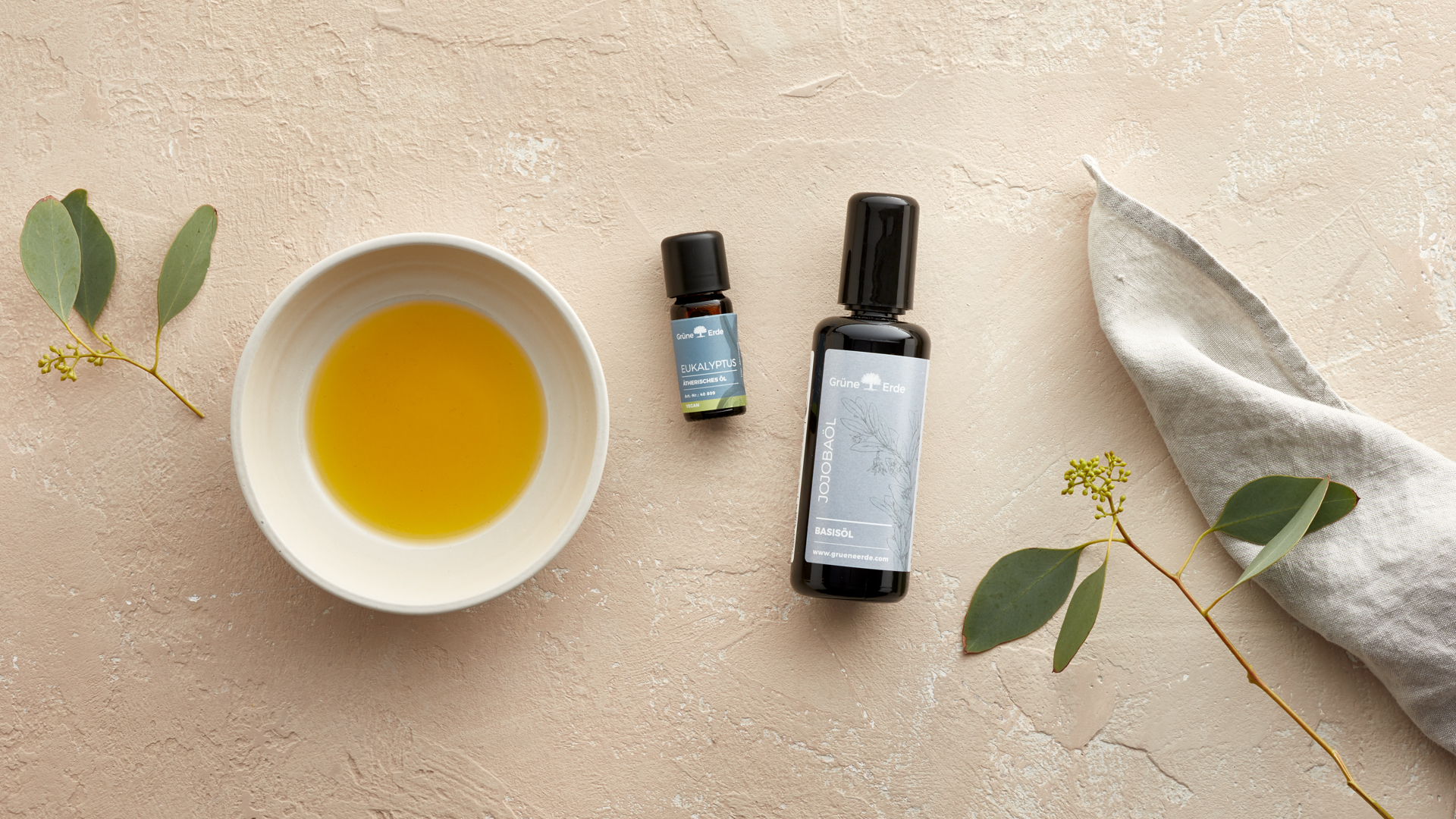 Basisöl und ätherisches Öl neben einer Schale mit Honig