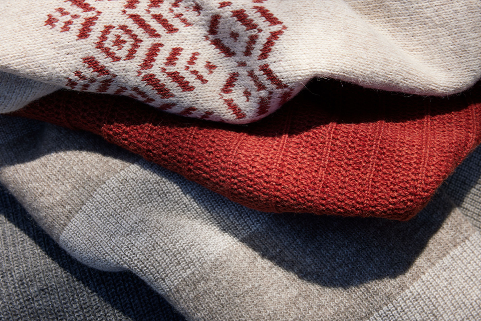 verschiedene Pullover in grauen und roten Tönen