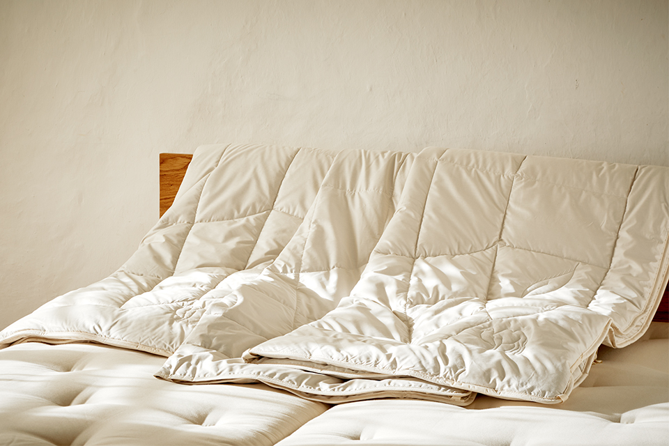 Zwei Bettdecken liegen über dem Kopfteil eines Bettes