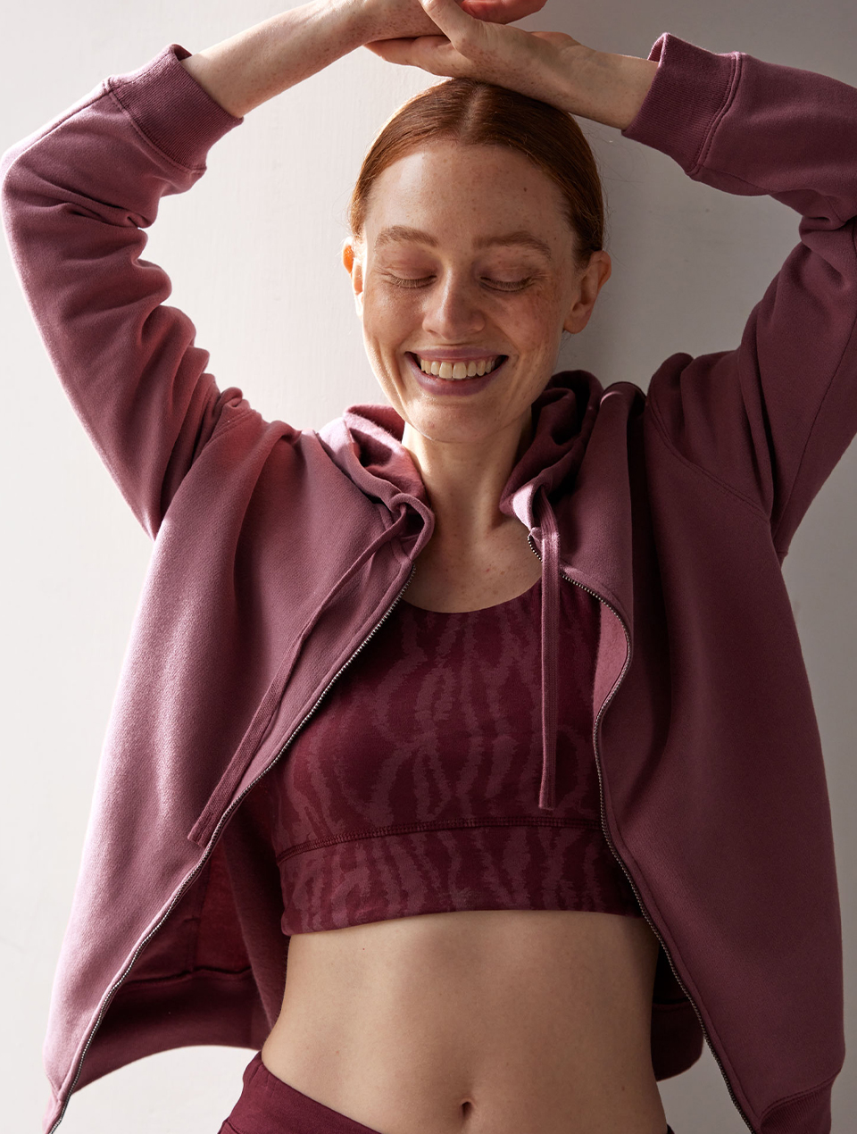 Frau trägt roten Yoga Bra und Sweatshirt