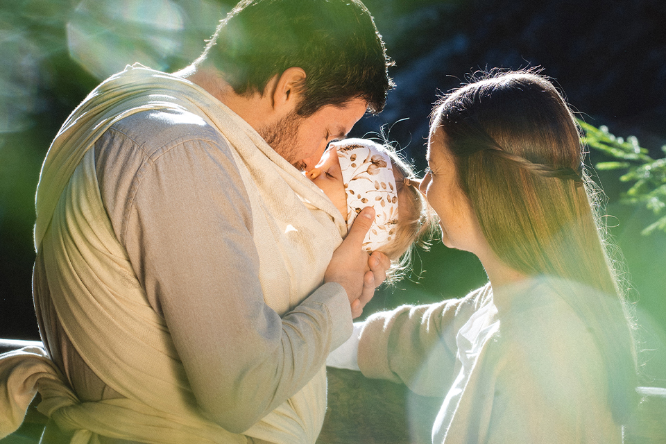 Vater trägt Baby im Tragetuch im Sonnenlicht
