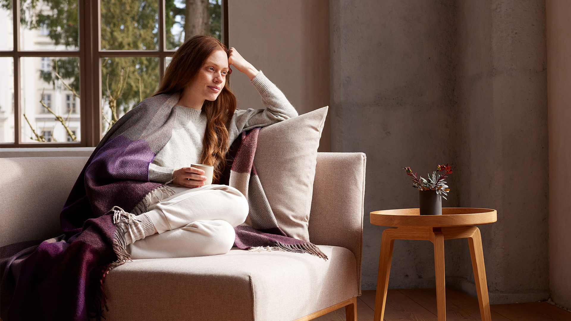 Entspannte Frau liest Buch auf Sofa bei gemütlichem Licht