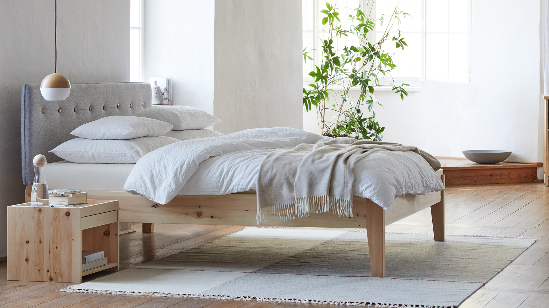 Bett aus Zirbe mit weißer Bettwäsche in hellem Raum