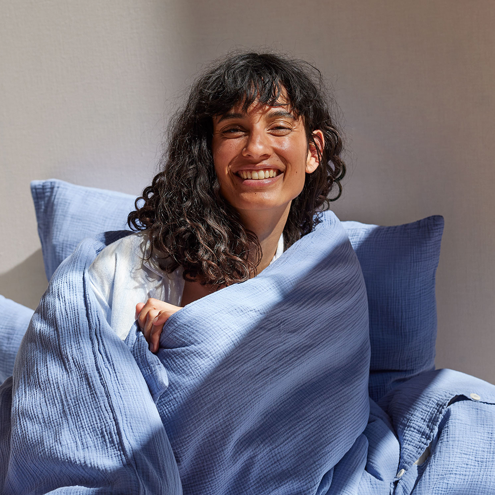 Frau in Bettdecke eingekuschelt