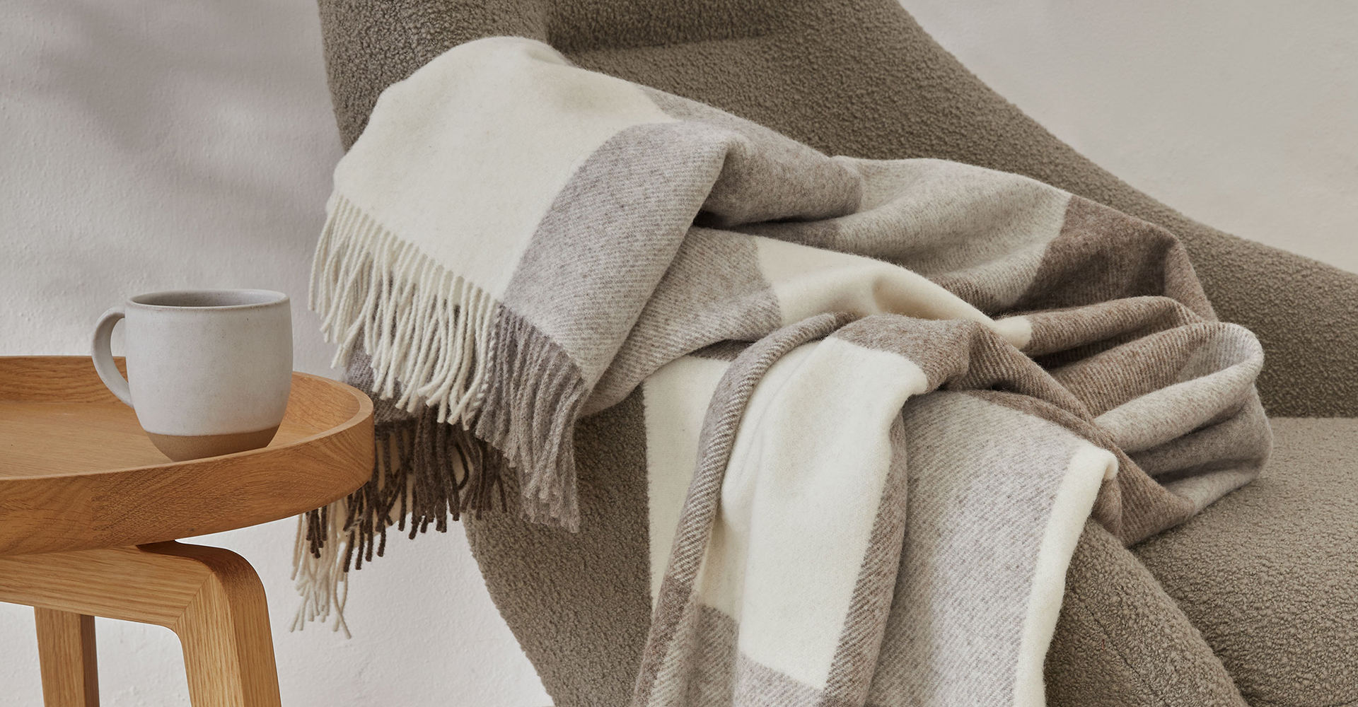 Beige und weiße Wohndecke auf Sofa liegend