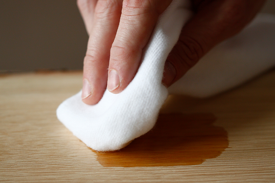 Holzplatte wird mit weißem Tuch eingeölt