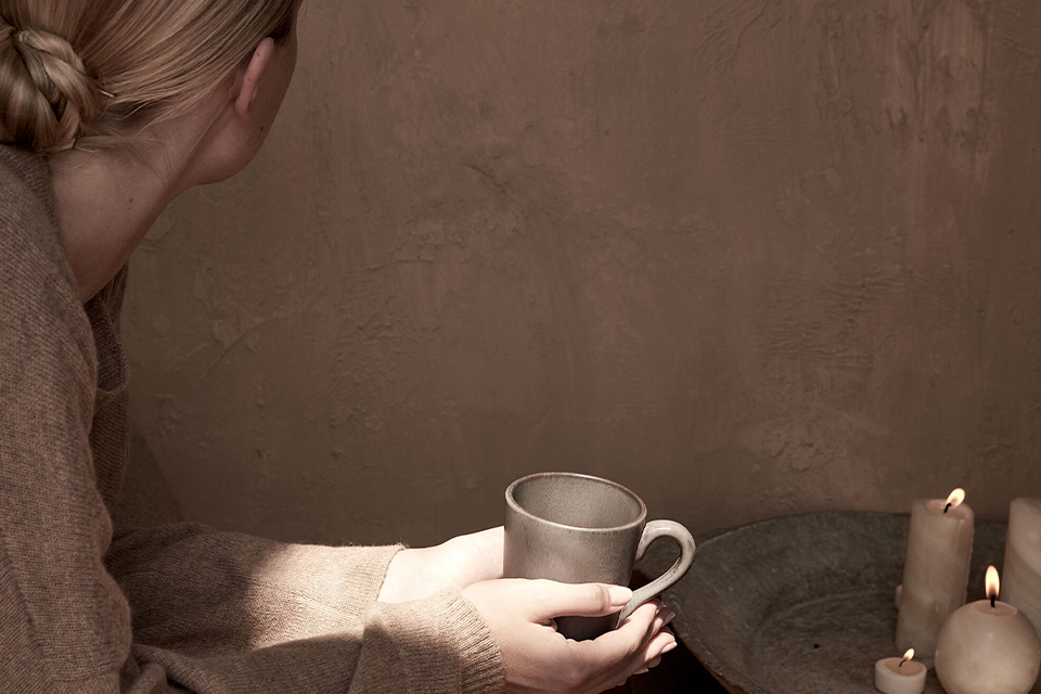Hände halten warme Tasse in ruhiger minimalistischer Umgebung