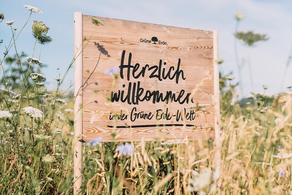 Holzschild mit der Aufschrift Herzlich Willkommen in der Grünen Erde Welt in der Natur