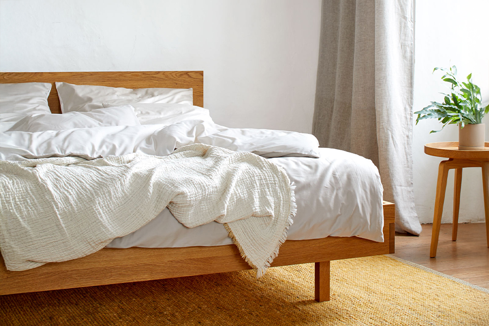 Bett Tesoro mit heller Bettwäsche vor einem großen Fenster