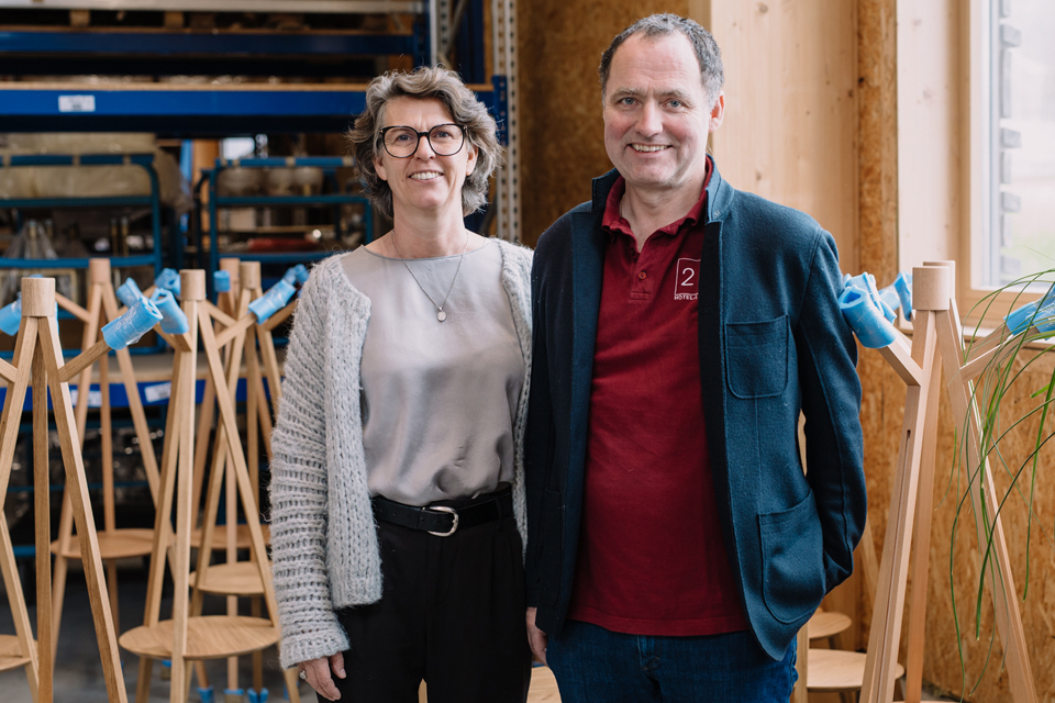 Lächelnde Frau und Mann stehen vor Holz-Prototypen