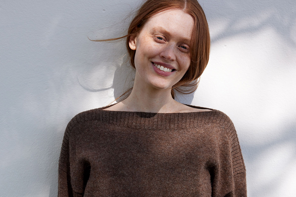 Lächelnde Frau im braunen Pullover im weichen Licht