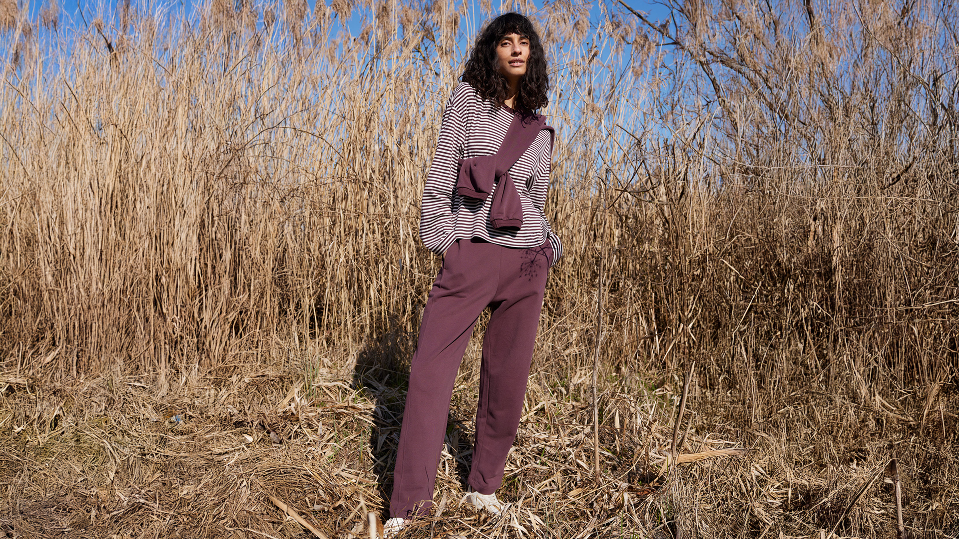 Frau im Feld trägt nachhaltige Mode in warmen Farben