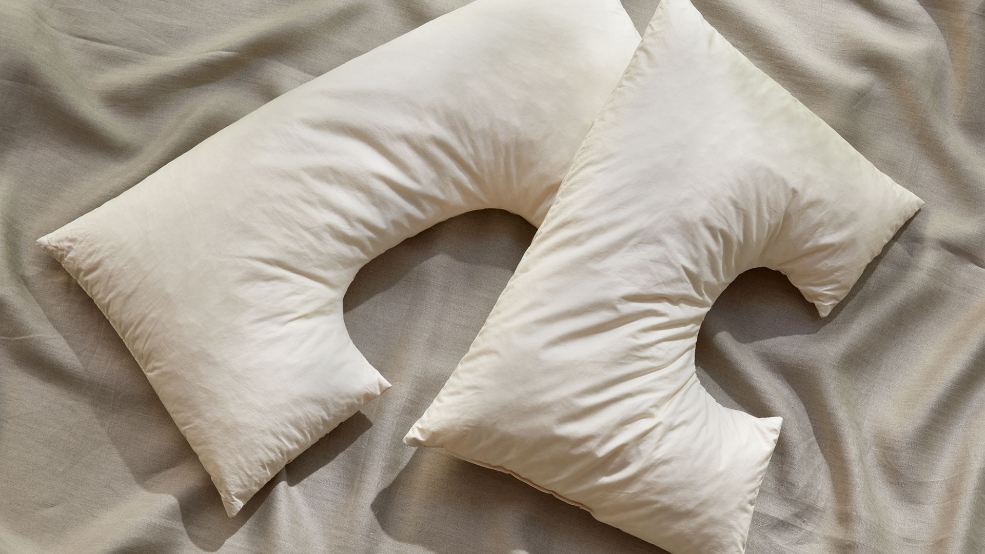 zwei Schulterkissen mit Ausnehmung liegen auf einem grauen Untergrund