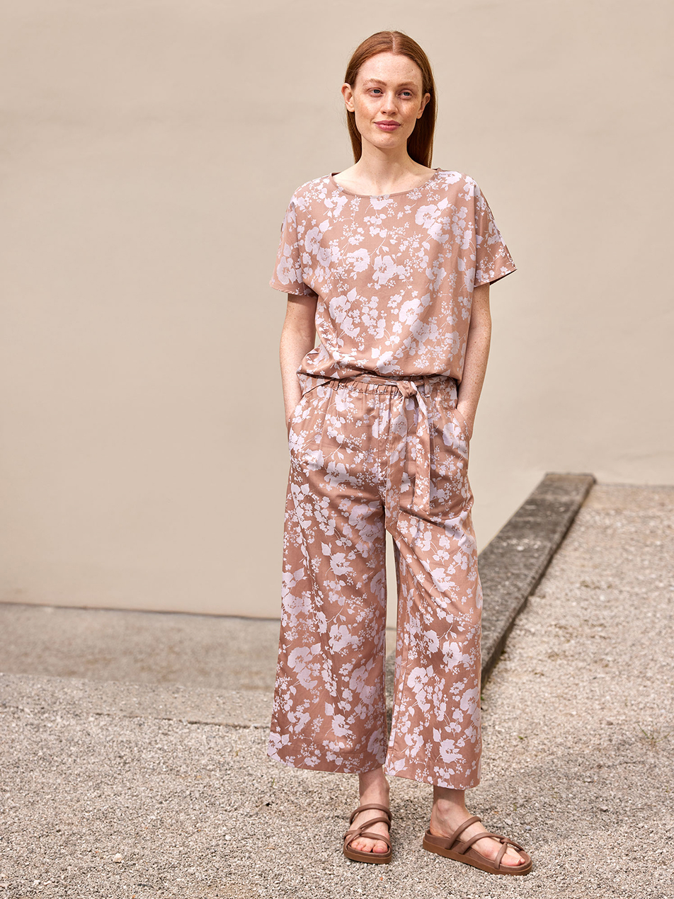 Frau trägt gemustertes Outfit mit weiter Hose und Sandalen