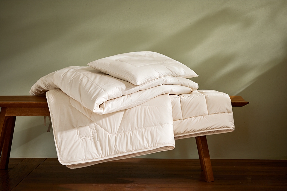 Zwei Bettdecken liegen auf einer dekorativen Holzbank