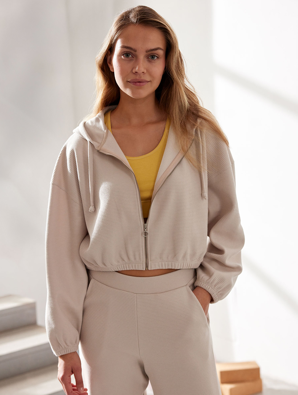 Frau im beigen Loungewear Set mit Waffelstruktur und gelbem Top