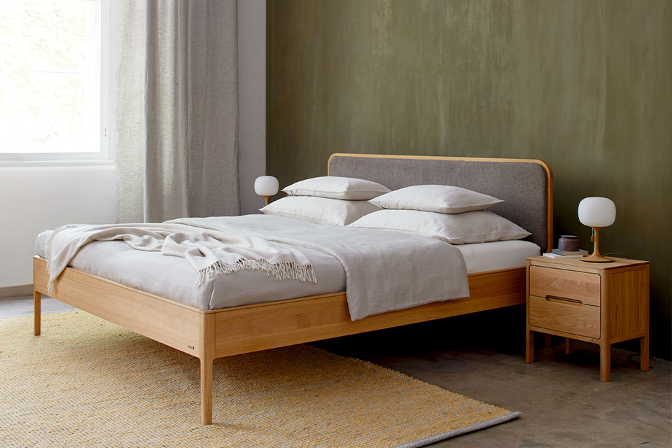 Modernes Schlafzimmer mit Holzbett und minimalistischer Einrichtung in warmen Farbtönen