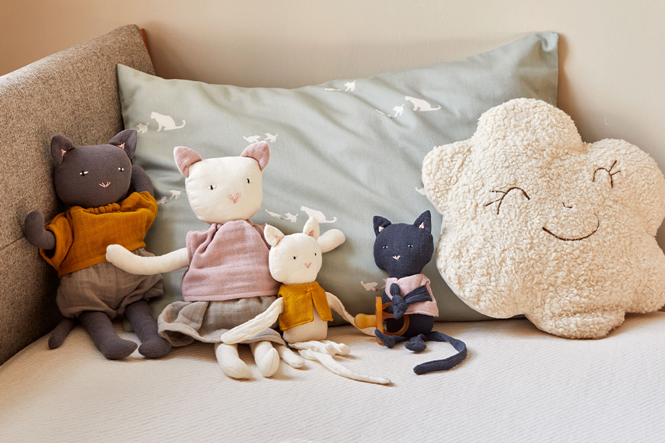 Kuscheltiere sitzen vor einem Kopfkissen auf einem Sofa