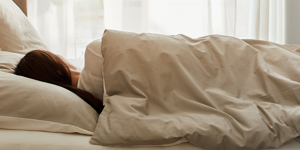 Frau liegt schlafend im Bett