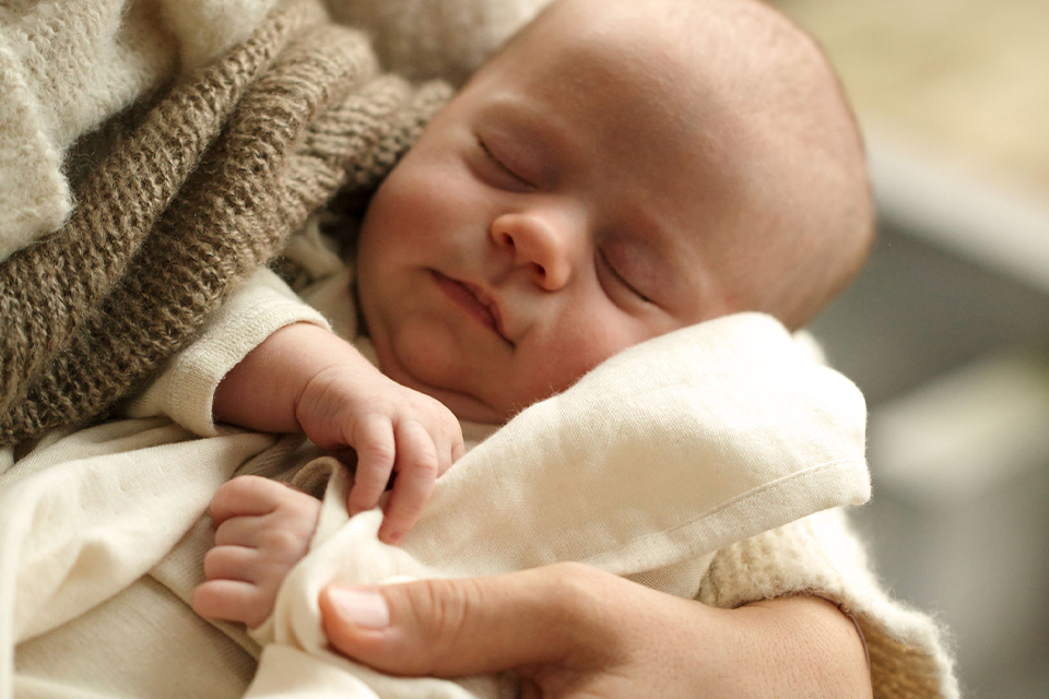 Ein schlafendes Baby in den Armen seiner Mutter