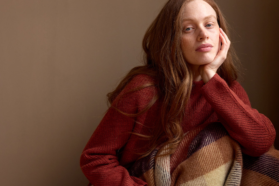 Junge Frau in rotem Pullover sitzt entspannt und schaut zur Seite