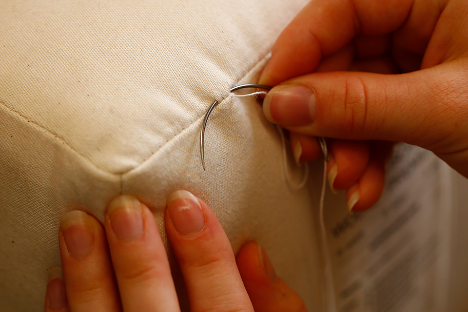 Hände nähen Stoff sorgfältig mit Nadel und Faden