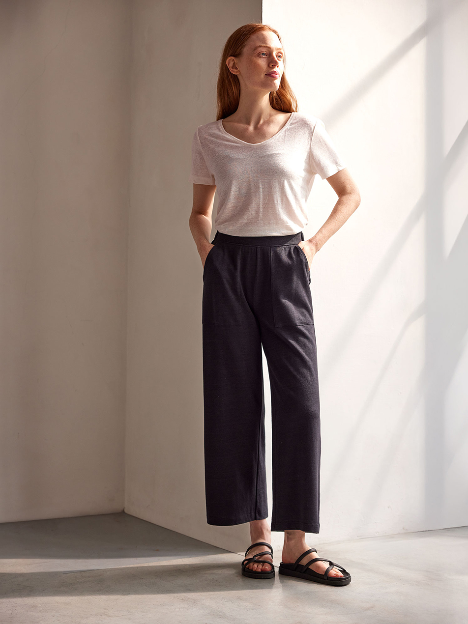 Frau trägt weißes Shirt und dunkle weite Hose mit Sandalen