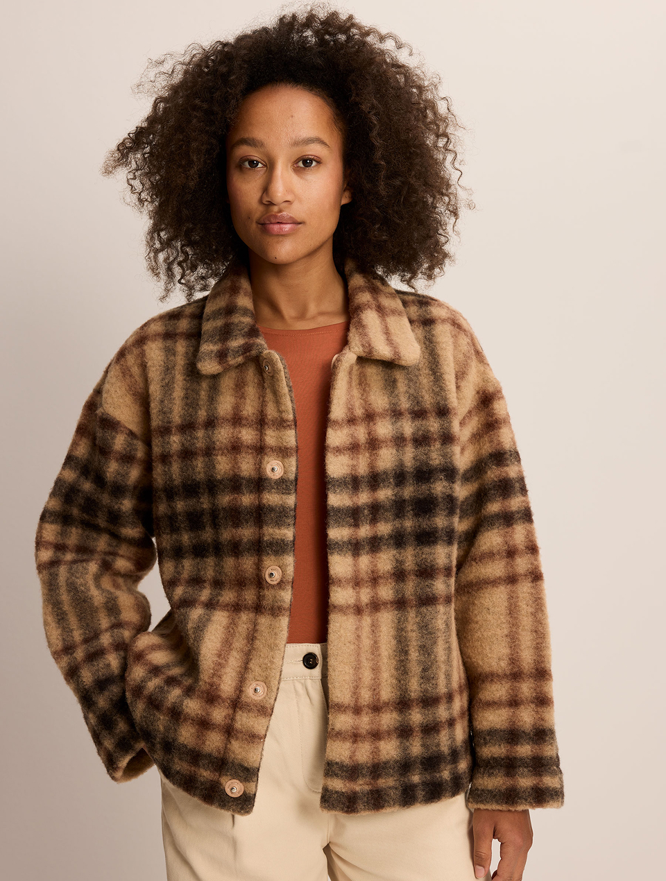 Frau mit dunklen Locken trägt eine karierte Wolljacke