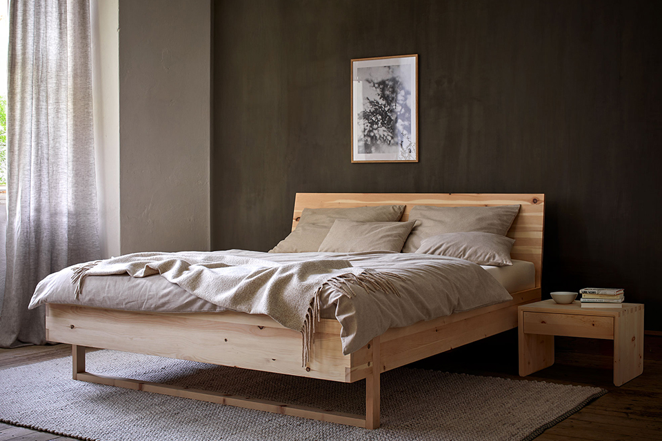 Zirbenbett Akato vor einer dunkelbraunen Wand